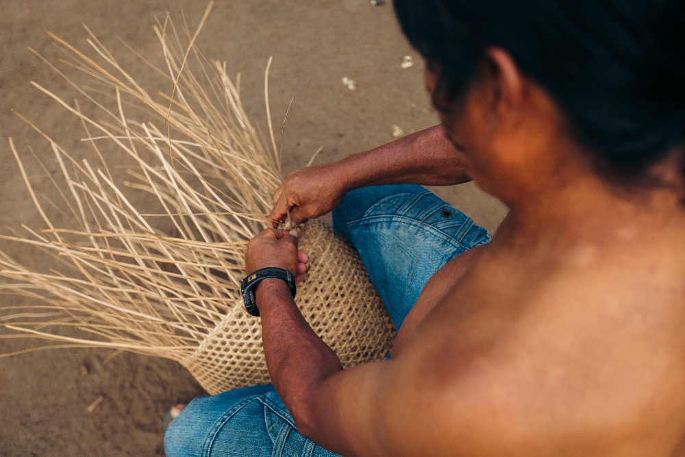 Top-down view of shirtless man basket-weaving