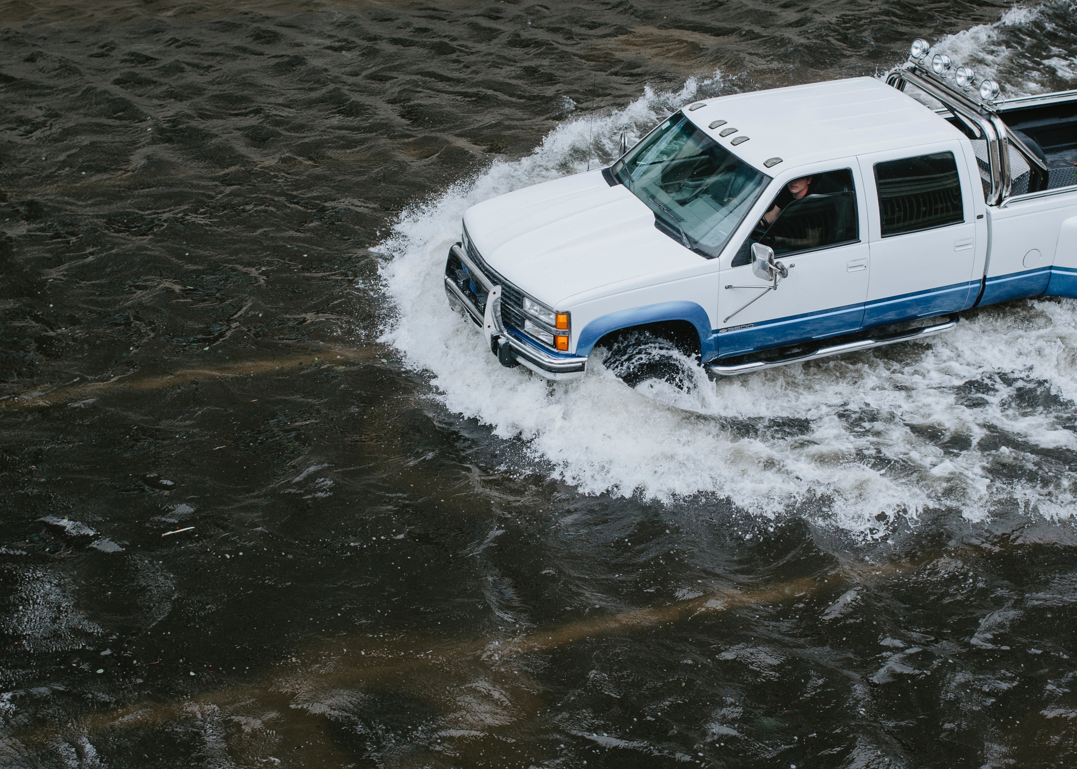 white truck driving through flooded streets