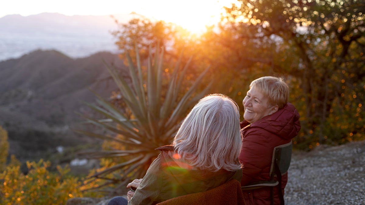 two-senior-women-nature-escapade-sitting-chairs-enjoying-their-time-1200x675