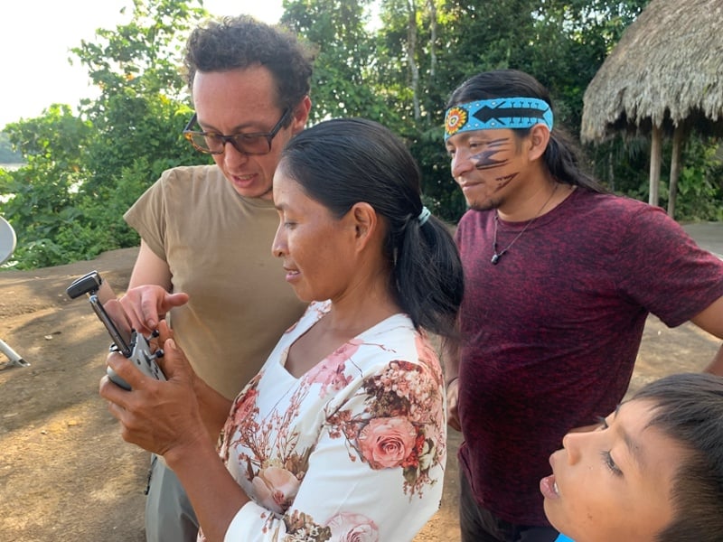 Achuar man, woman, and child learning how to use a drone