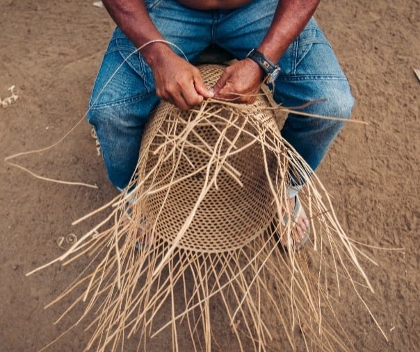 man weaving basket using traditional materials