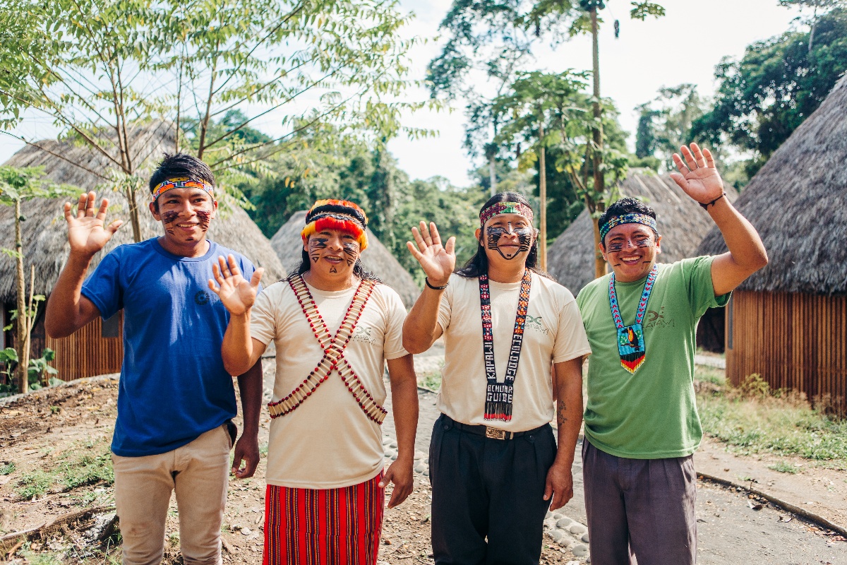 four Achuar men waving and smiling 